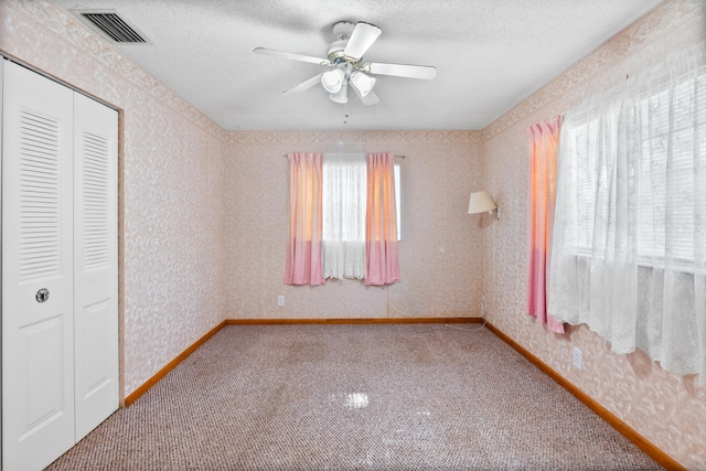 unfurnished bedroom featuring ceiling fan, carpet, a closet, and multiple windows