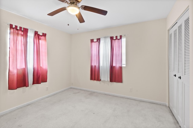 unfurnished bedroom featuring ceiling fan, light colored carpet, and a closet