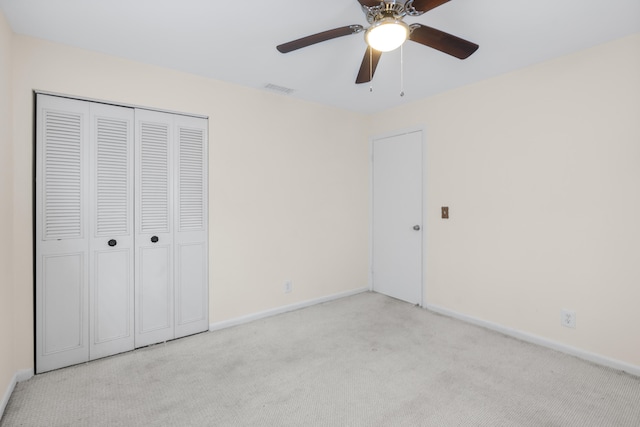 unfurnished bedroom featuring ceiling fan, light colored carpet, and a closet