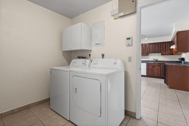 laundry area with light tile patterned floors, independent washer and dryer, a textured ceiling, and cabinets