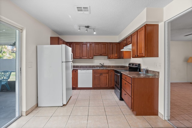 kitchen featuring a textured ceiling, light tile patterned flooring, sink, and white appliances