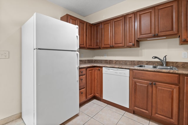 kitchen featuring sink, white appliances, light tile patterned floors, and a textured ceiling