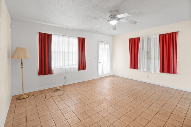 empty room featuring a textured ceiling, ceiling fan, and light tile patterned flooring