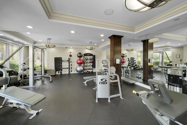 gym featuring a tray ceiling, decorative columns, and ornamental molding