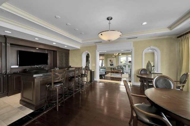 bar with crown molding, a tray ceiling, light hardwood / wood-style floors, dark brown cabinetry, and a chandelier