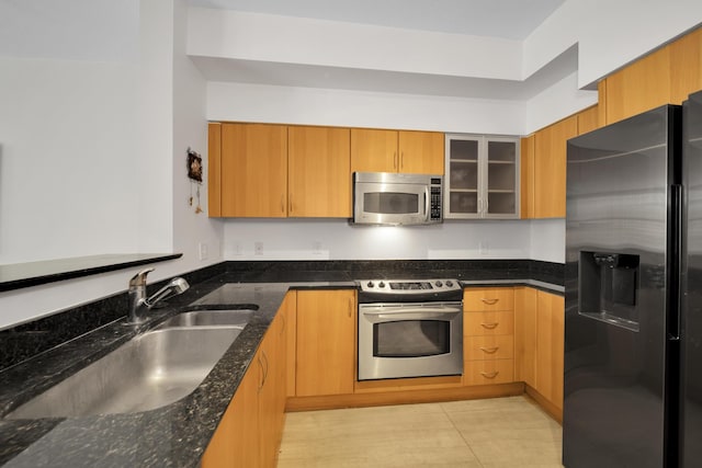 kitchen with stainless steel appliances, dark stone countertops, and sink