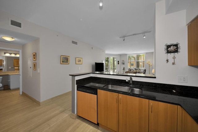 kitchen featuring dishwashing machine, light wood-type flooring, sink, and dark stone countertops