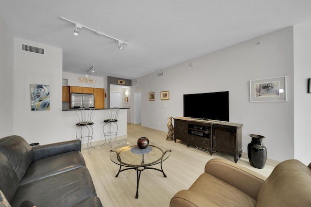 living room featuring rail lighting and light hardwood / wood-style flooring