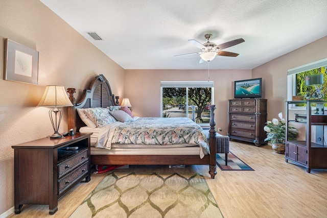 bedroom featuring ceiling fan, light hardwood / wood-style floors, and a textured ceiling