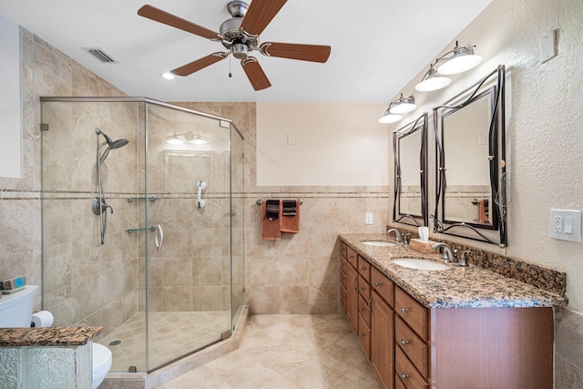 bathroom with tile walls, vanity, a shower with door, and toilet