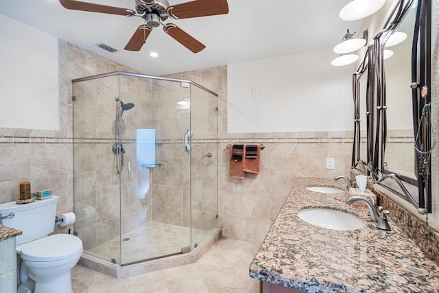 bathroom featuring vanity, toilet, a shower with shower door, and tile walls