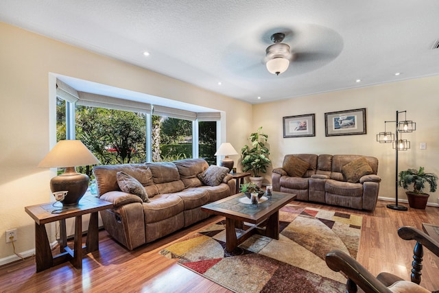 living room featuring hardwood / wood-style floors, a textured ceiling, and ceiling fan