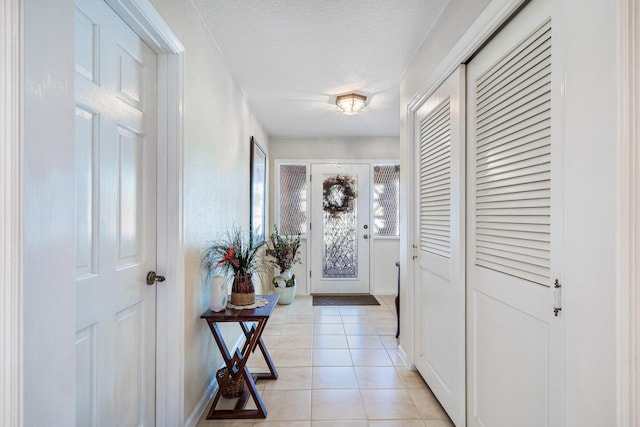 entryway with light tile patterned floors and a textured ceiling