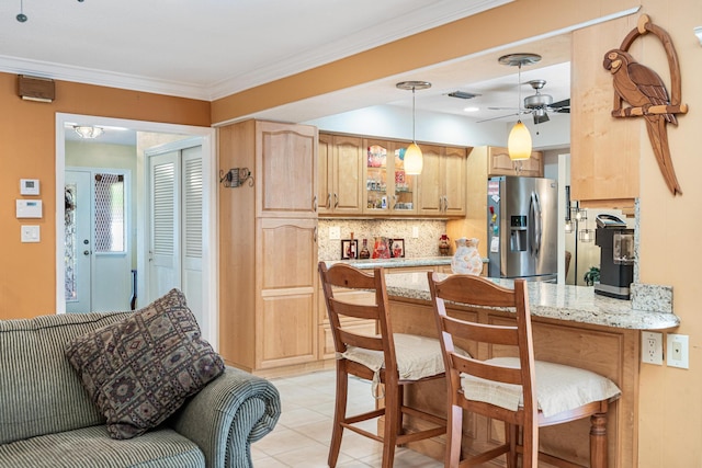 kitchen with stainless steel fridge, light stone counters, ornamental molding, decorative backsplash, and kitchen peninsula