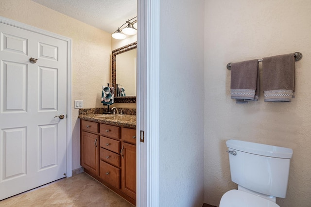 bathroom featuring vanity, tile patterned flooring, and toilet