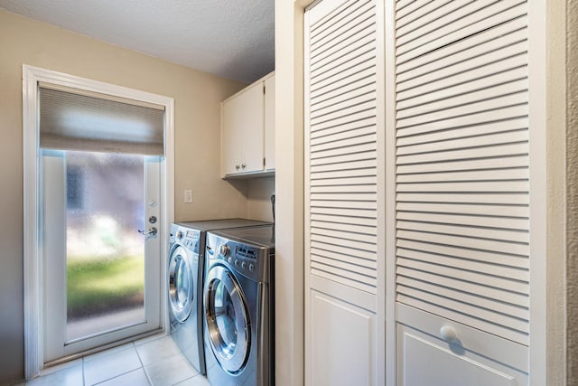 clothes washing area with plenty of natural light, cabinets, washer and dryer, a textured ceiling, and light tile patterned flooring