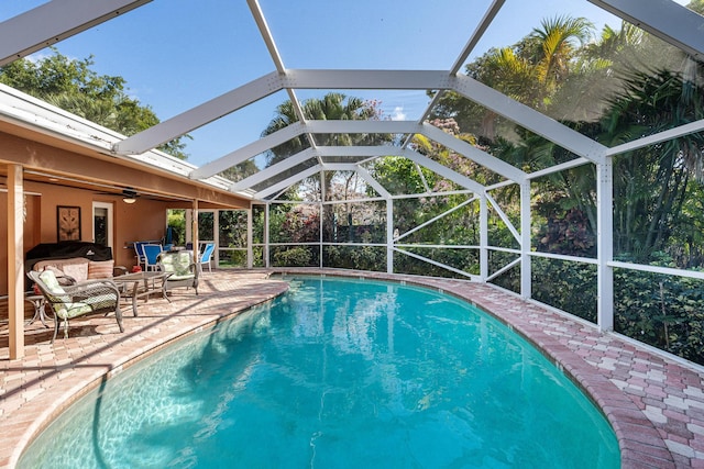 view of swimming pool featuring an outdoor living space, a lanai, a patio area, and ceiling fan