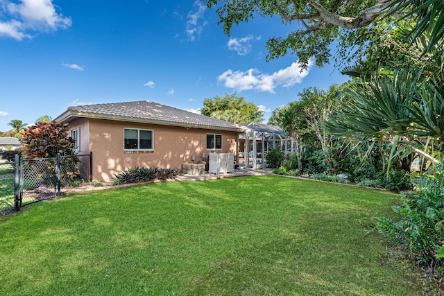 back of property featuring a yard and glass enclosure