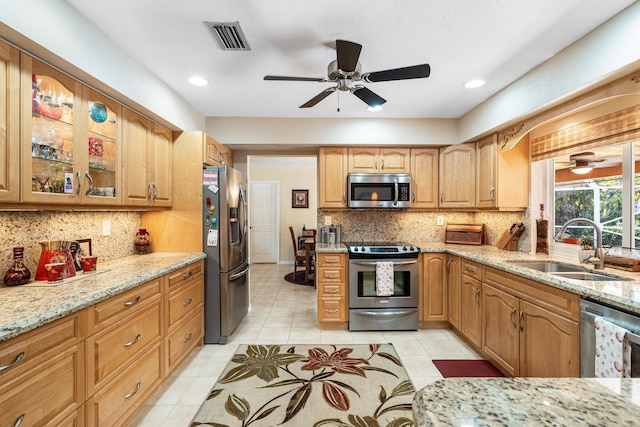 kitchen featuring sink, light tile patterned floors, appliances with stainless steel finishes, backsplash, and light stone countertops