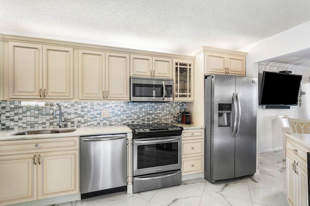 kitchen with cream cabinetry, sink, appliances with stainless steel finishes, and tasteful backsplash