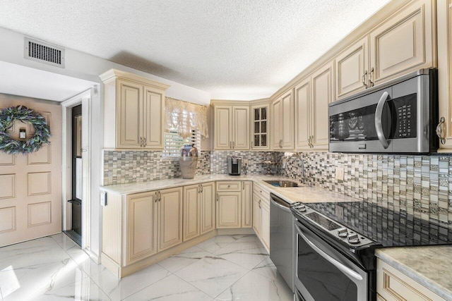 kitchen featuring a textured ceiling, sink, appliances with stainless steel finishes, and tasteful backsplash