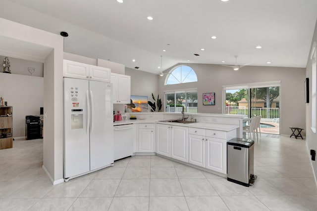 kitchen with kitchen peninsula, white appliances, sink, white cabinetry, and lofted ceiling