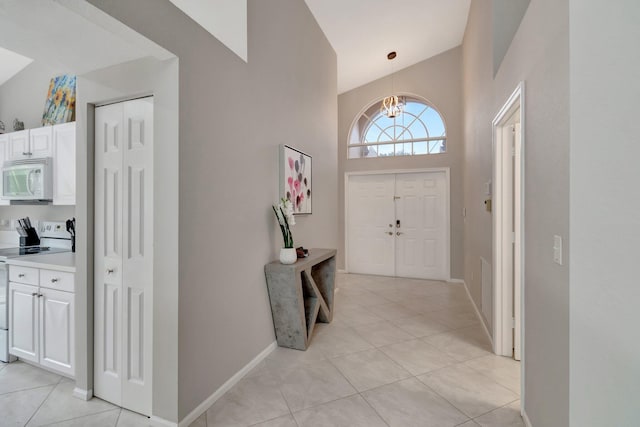 entrance foyer with light tile patterned floors, high vaulted ceiling, and a notable chandelier