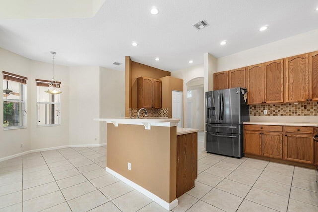 kitchen with backsplash, pendant lighting, light tile patterned floors, and stainless steel refrigerator with ice dispenser