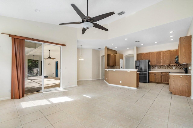 kitchen featuring stainless steel refrigerator with ice dispenser, tasteful backsplash, ceiling fan, light tile patterned floors, and decorative light fixtures