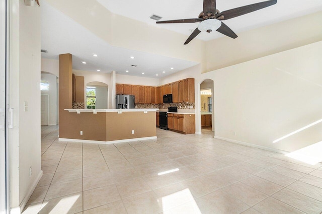 kitchen featuring backsplash, a center island, light tile patterned floors, and black appliances