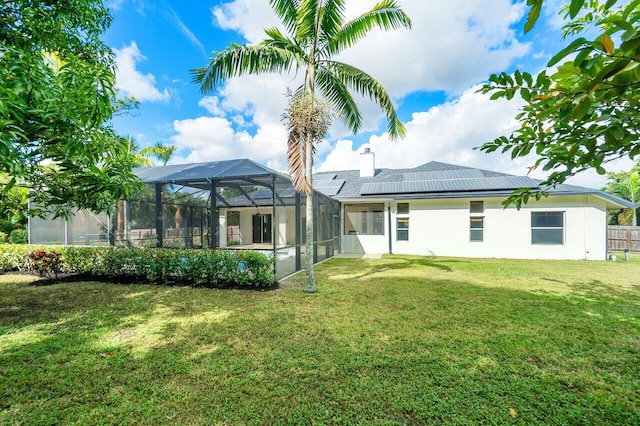 back of property with a lanai, a yard, and solar panels