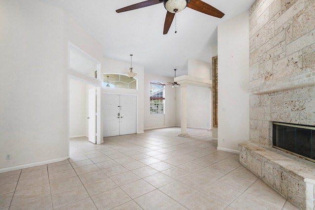 interior space featuring ceiling fan, light tile patterned flooring, and a stone fireplace