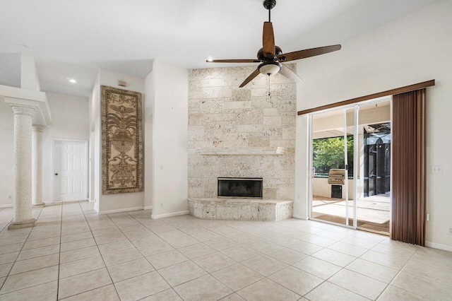 unfurnished living room with ceiling fan, a stone fireplace, ornate columns, and light tile patterned floors