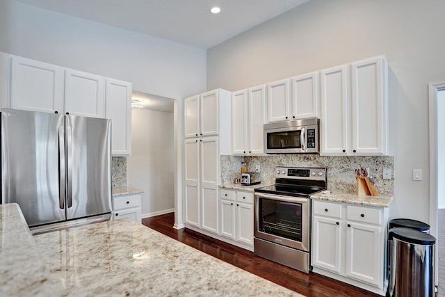 kitchen with white cabinetry, dark wood-type flooring, stainless steel appliances, and light stone counters