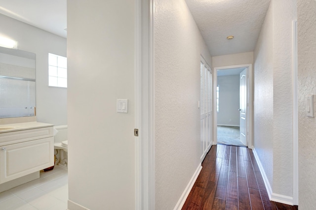 hall with a textured ceiling and light wood-type flooring