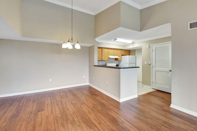 kitchen featuring ornamental molding, decorative light fixtures, white fridge, kitchen peninsula, and a chandelier