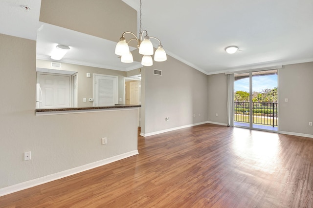 empty room featuring hardwood / wood-style floors, an inviting chandelier, and ornamental molding