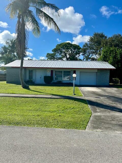 single story home featuring a garage and a front lawn