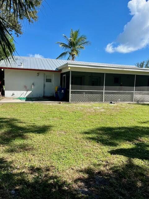 back of property featuring a lawn and a sunroom