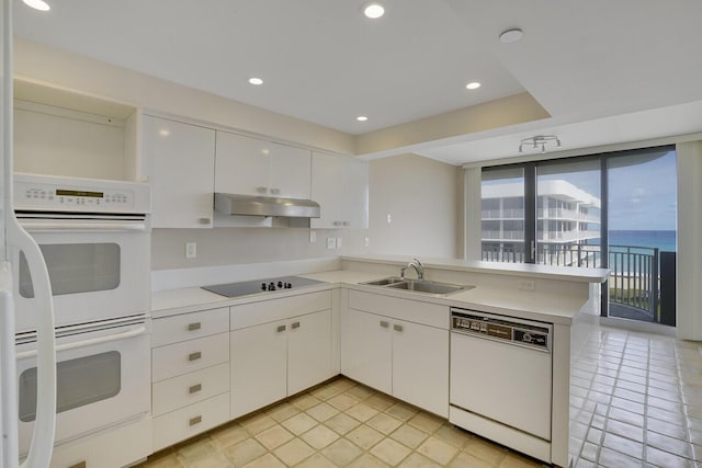 kitchen featuring sink, white cabinets, kitchen peninsula, white appliances, and a water view