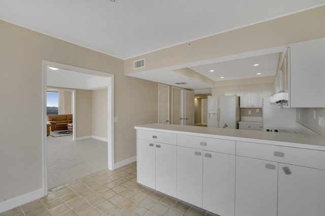 kitchen with light carpet, white cabinets, a raised ceiling, white fridge with ice dispenser, and cooktop