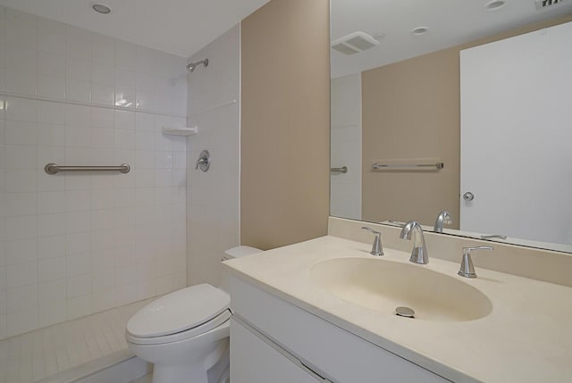 bathroom featuring a tile shower, vanity, and toilet