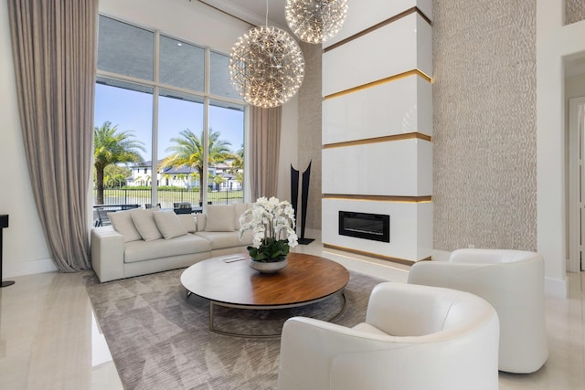 living area featuring a glass covered fireplace, a notable chandelier, and a towering ceiling