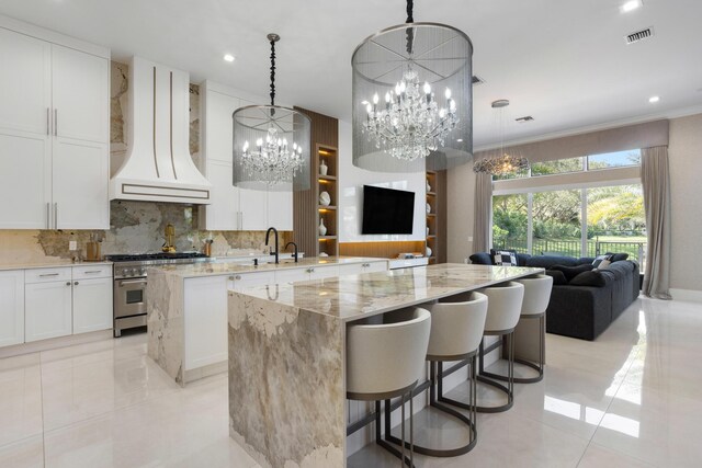 kitchen featuring white cabinetry, sink, hanging light fixtures, ornamental molding, and light stone countertops