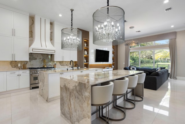 kitchen featuring a center island, custom exhaust hood, high end stainless steel range, visible vents, and open floor plan