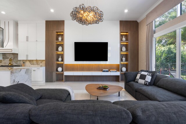 kitchen featuring a kitchen island with sink, sink, light stone counters, and an inviting chandelier