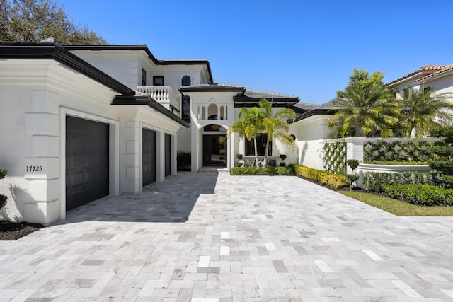 view of front of house featuring a balcony, decorative driveway, and stucco siding