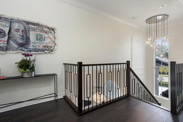 hall with ornamental molding, wood finished floors, an upstairs landing, and an inviting chandelier