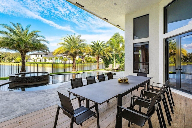 wooden terrace with a water view and french doors