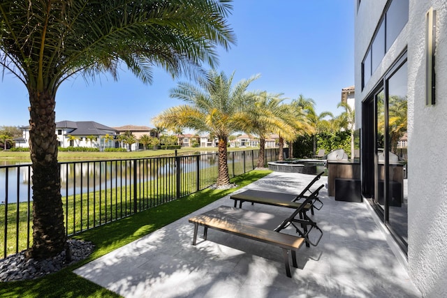 surrounding community featuring a water view, a lawn, a patio area, exterior kitchen, and a fenced backyard